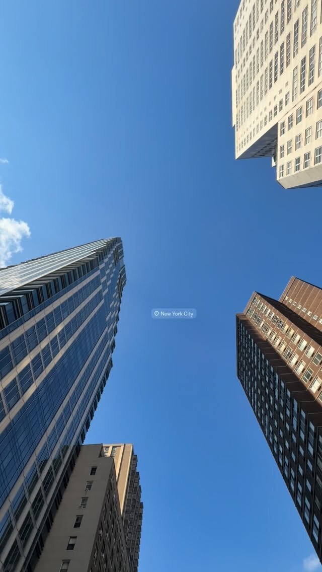 Looking straight up at NYC skyscrapers against a clear blue sky
