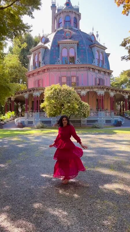 Roopsi Bansal twirling in a red ruffled Chicwish dress in front of the pink domed Armour-Stiner Octagon House in Irvington, New York