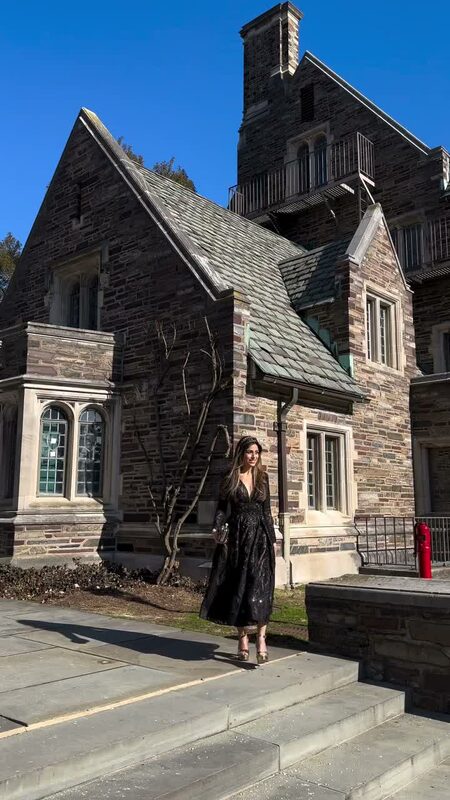 Roopsi Bansal in a black dress from New York Dress carrying a Jaipur Rose clutch in front of a Gothic stone building