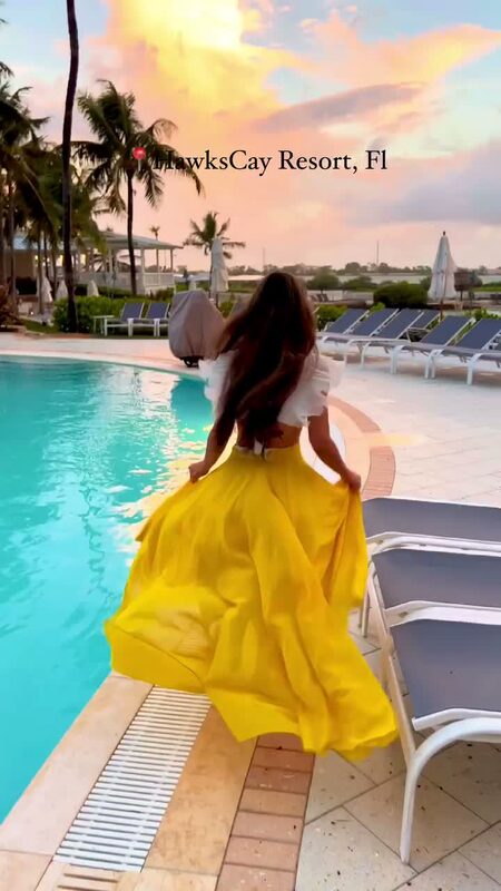 Roopsi Bansal in a yellow skirt and white top running alongside a pool at sunset at Hawks Cay Resort in the Florida Keys