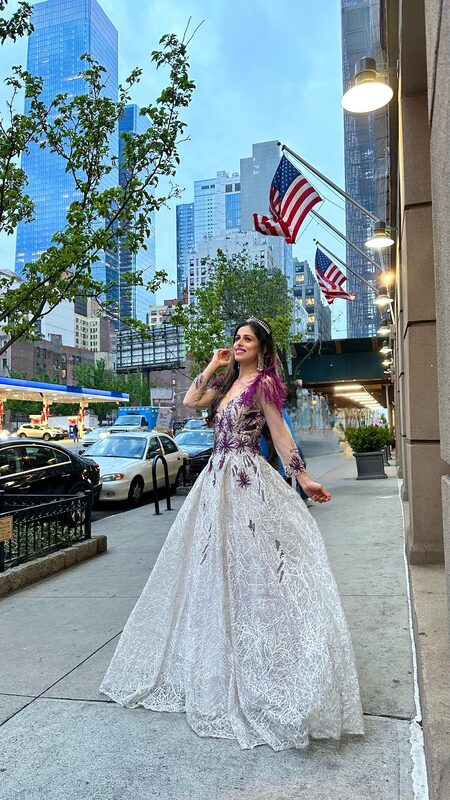 Roopsi Bansal in a tiara and embellished ballgown standing on a New York City sidewalk outside The Queen's Ball: A Bridgerton Experience