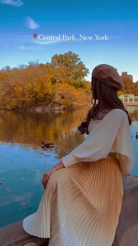 Roopsi Bansal in a cream cardigan and brown beret sitting by the Central Park lake watching a duck swim past