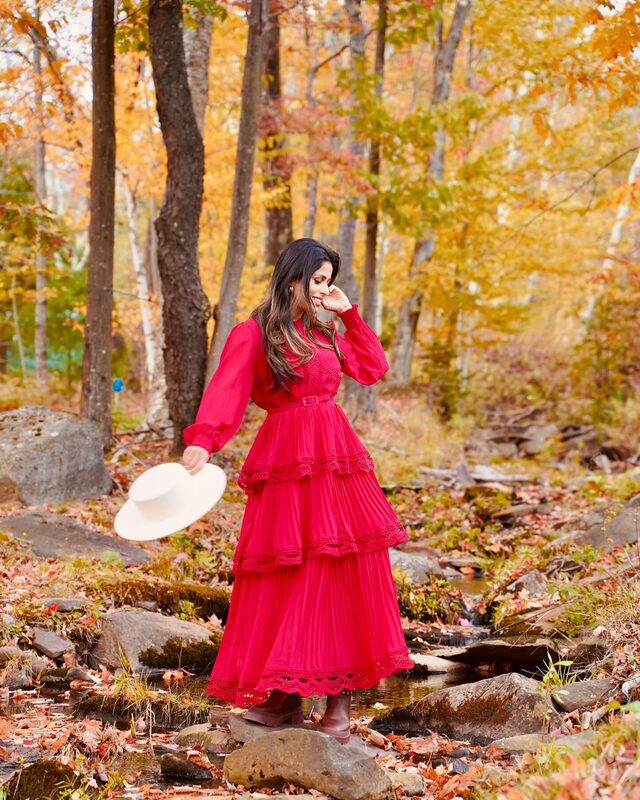 Roopsi Bansal in a red ruffled maxi dress from Chicwish standing among rocks in a stream in the Catskills, New York