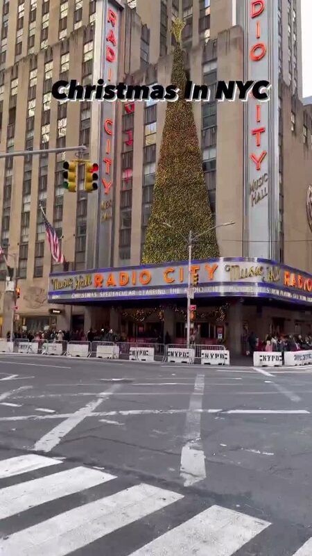 Radio City Music Hall's marquee and a lit Christmas tree on the street corner outside in New York City