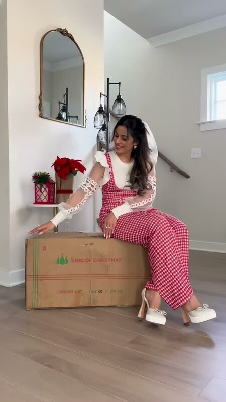 Roopsi Bansal preparing holiday decor with King of Christmas, wearing a Chicwish jumpsuit