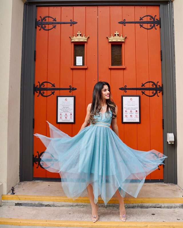 Roopsi Bansal in a sky blue handkerchief-hem tulle dress from EverPretty, twirling in front of the orange doors of the Cathedral Basilica of St. Augustine