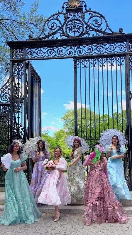 Roopsi Bansal and five friends in pastel Selkie dresses with parasols in front of the Vanderbilt Gate at the Conservatory Garden in Central Park