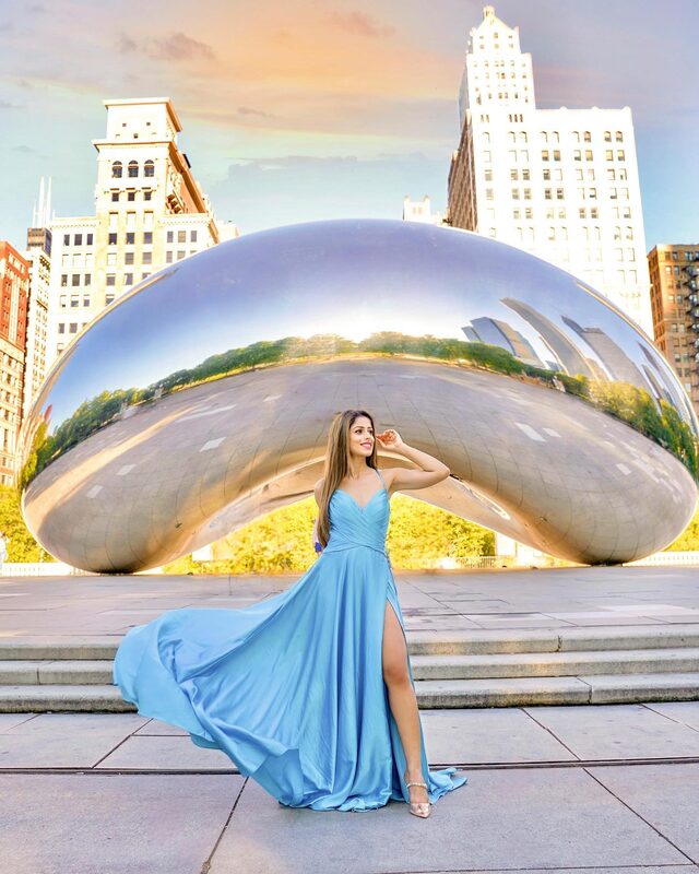 Roopsi Bansal in a cloud blue flowing gown with a thigh slit, posing in front of Cloud Gate at Millennium Park in Chicago at sunset