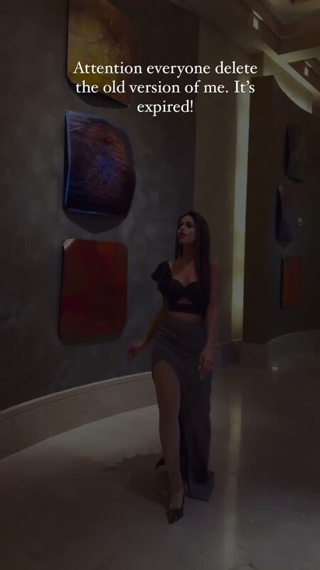 Roopsi Bansal in a black crop top and glittering silver slit skirt in a hallway lined with framed abstract art
