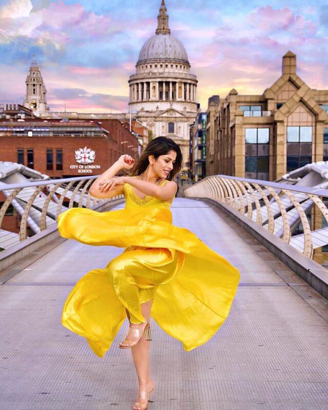 Roopsi Bansal in a flowing yellow dress caught mid-twirl on the Millennium Bridge, with St Paul's Cathedral in the background