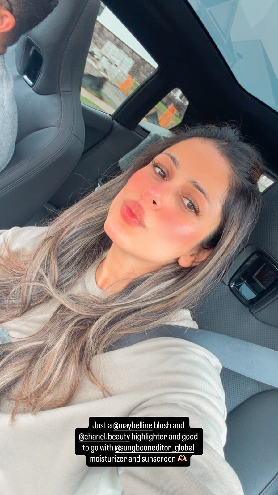 Roopsi Bansal taking a car selfie under a sunroof, wearing pink blush