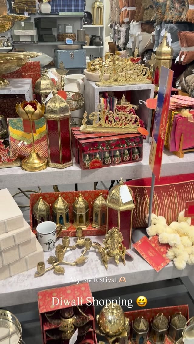 Store shelves full of gold lanterns, brass diyas and red and gold Diwali decorations