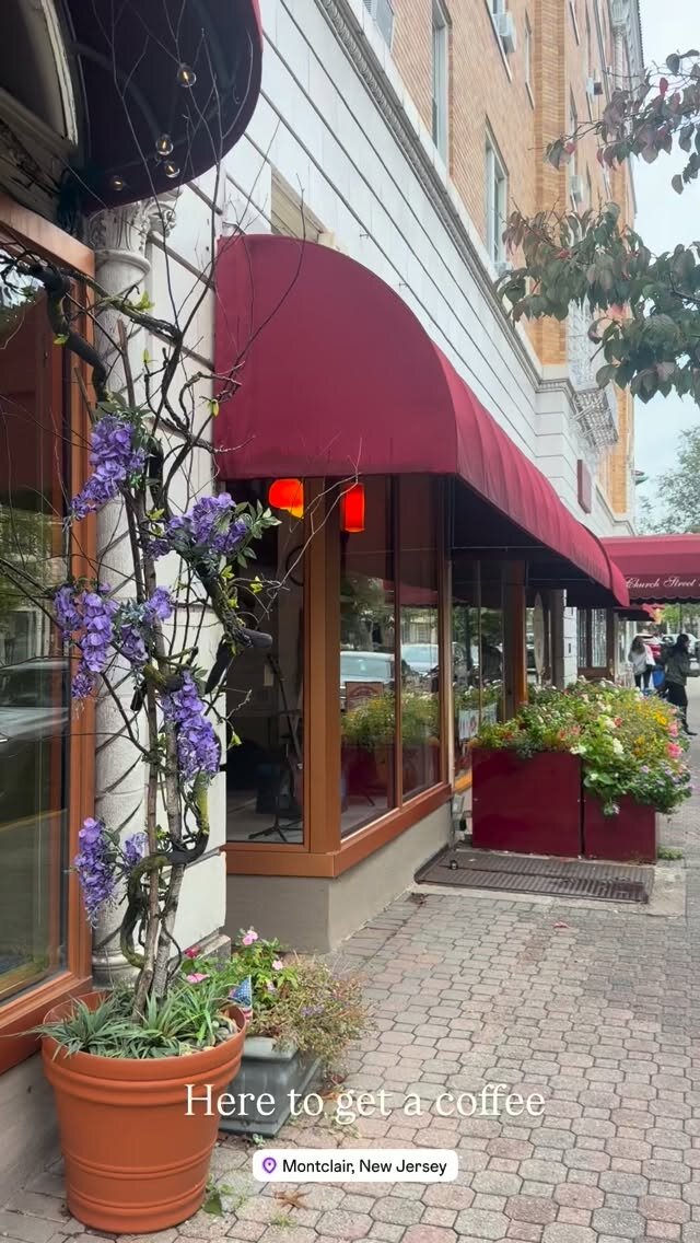 A Montclair, New Jersey sidewalk with red awnings, planters and purple flowers