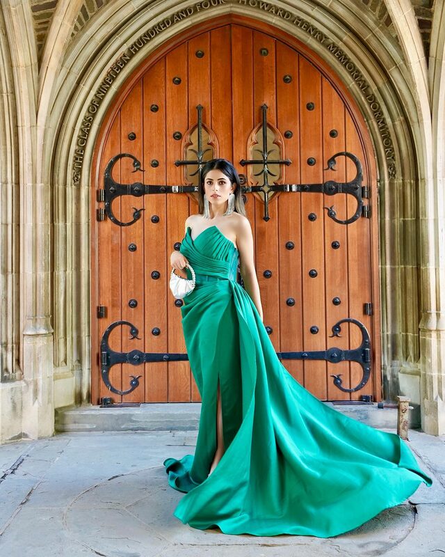 Roopsi Bansal in a strapless emerald green gown from New York Dress in front of the wooden doors of Princeton University's Howard Henry Memorial Dormitory