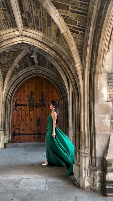 Roopsi Bansal in a strapless emerald green gown from New York Dress beside a heavy wooden Gothic door at Princeton University