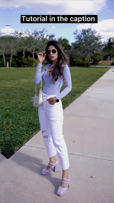 Roopsi Bansal in a lavender long-sleeve bodysuit and white ripped jeans, sunglasses pushed up, standing in a park