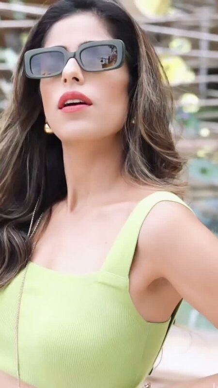 Close-up of Roopsi Bansal in rectangular sunglasses and a lime green top, filmed outdoors