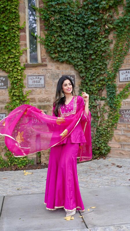 Roopsi Bansal in a magenta sharara set from The Loom in front of an ivy-covered stone wall with class reunion plaques