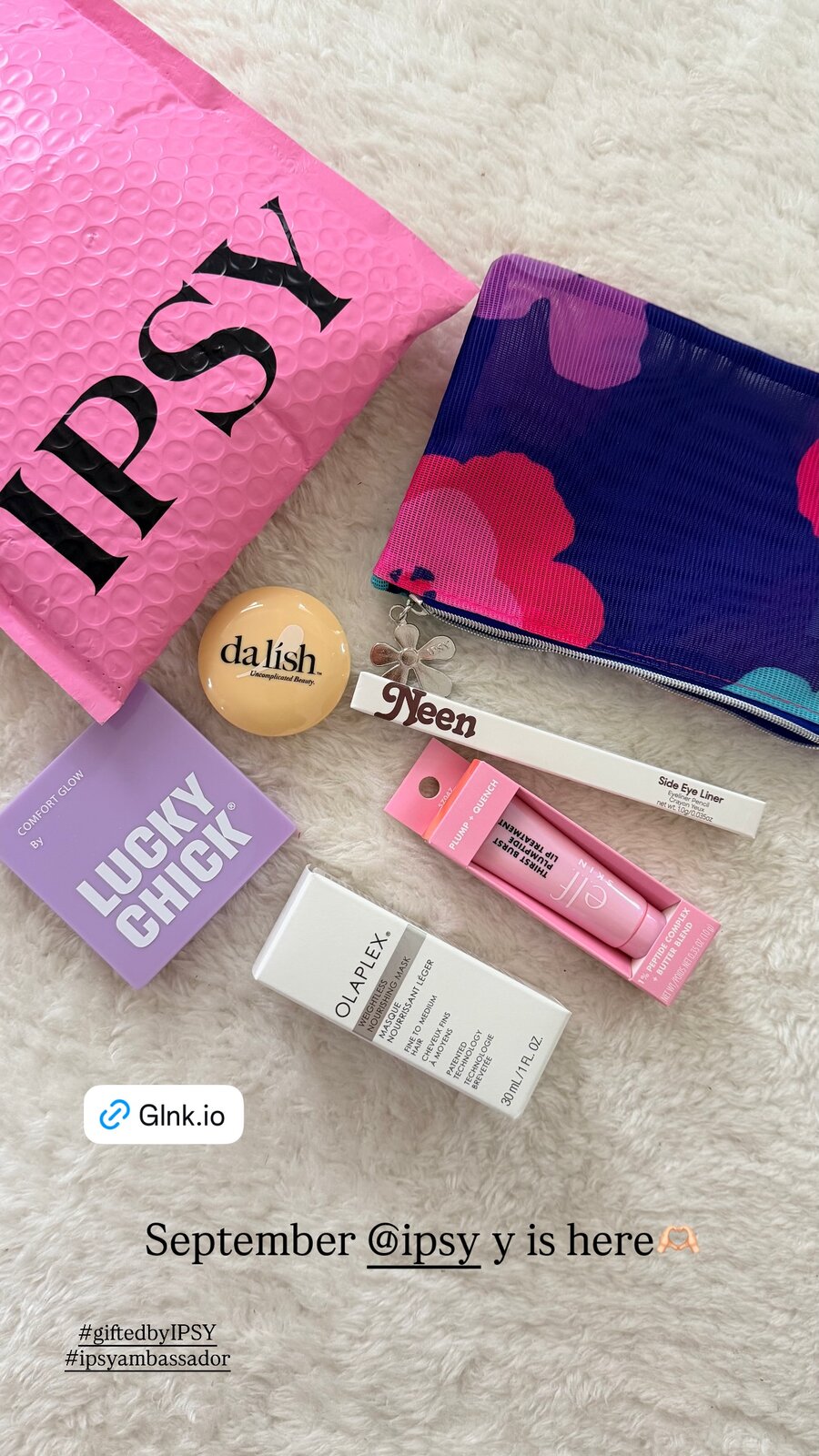 September's IPSY beauty bag unboxed, with a makeup pouch, lip treatment, eyeliner, and hair mask