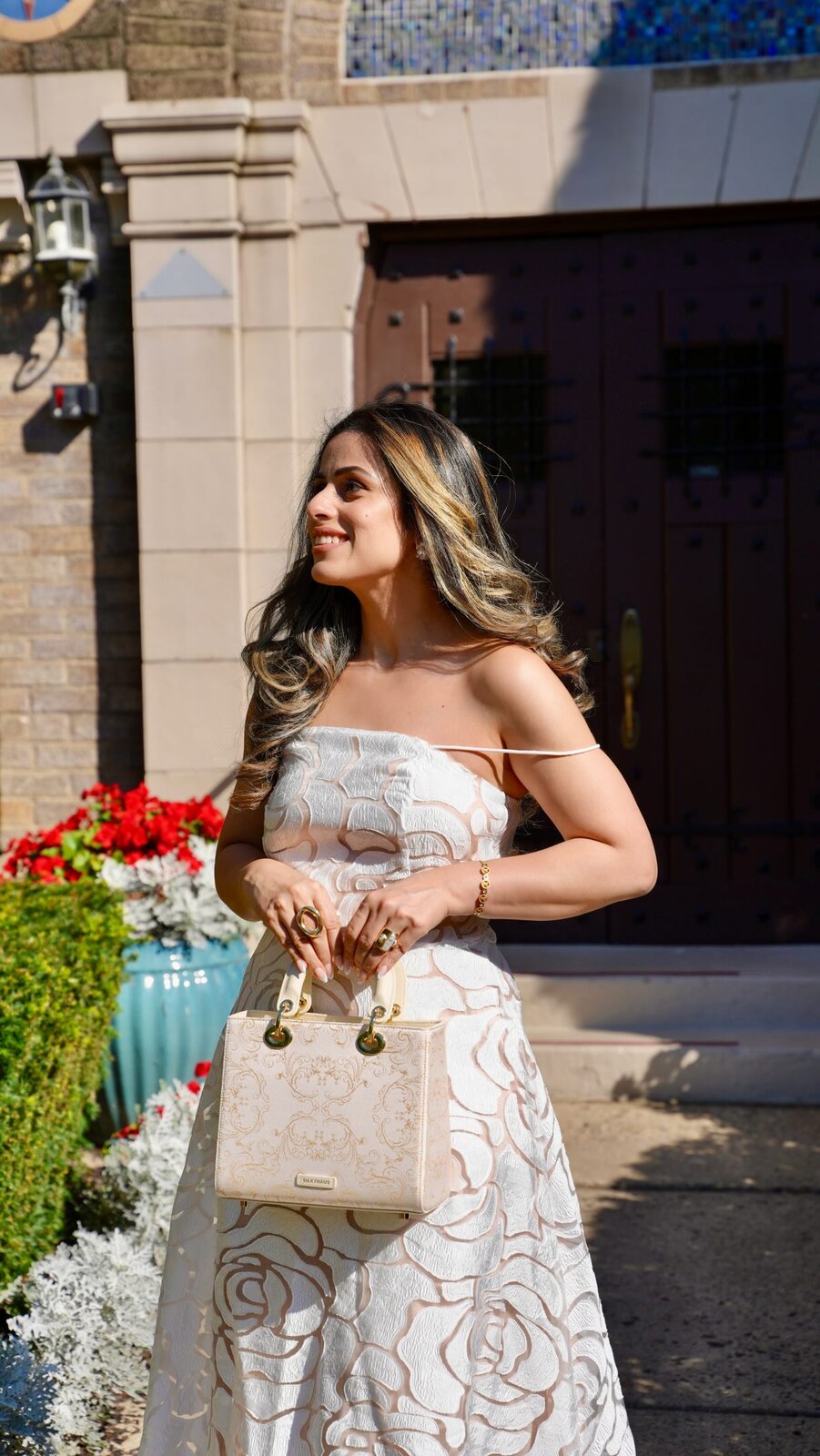 Roopsi Bansal posing with a Silkyhaus handbag in a white embroidered dress