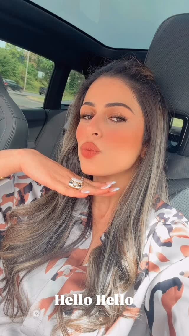Roopsi Bansal blowing a kiss in a car, wearing a floral shirt