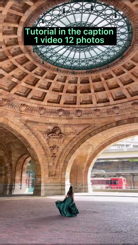 Roopsi Bansal from behind in a flowing emerald green satin gown, standing beneath a domed stone rotunda with arched openings and a red trolley visible outside