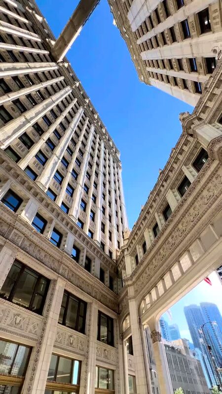 A low-angle view straight up at the Wrigley Building's white terracotta towers against a clear blue sky in Chicago