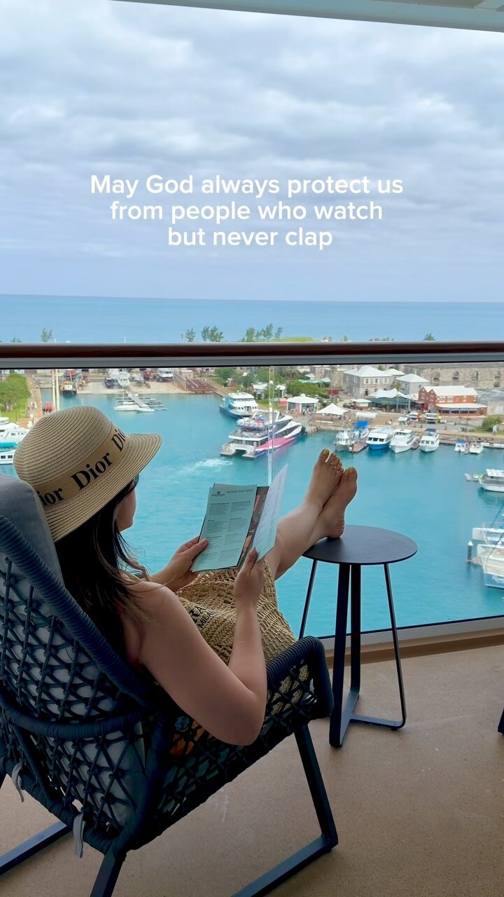 Roopsi Bansal in a straw Dior hat, feet up on a balcony overlooking a harbor full of boats, reading a menu