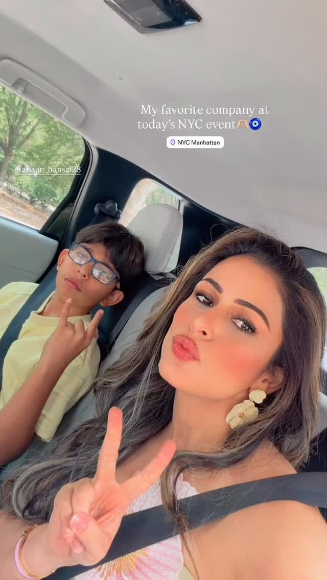 Roopsi Bansal and her son taking a selfie in the car on the way to an NYC event, her son making a peace sign in the back seat
