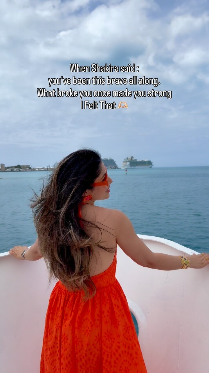 Roopsi Bansal in an orange sundress looking out at the ocean from a cruise ship deck