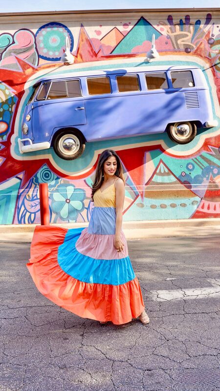 Roopsi Bansal in a tiered color-block maxi dress twirling in front of a colorful VW-bus street mural in Atlanta