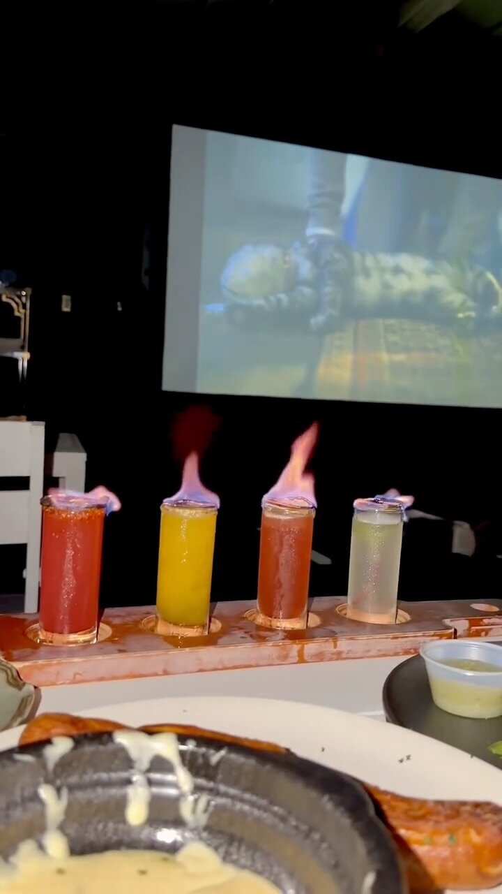 A flaming flight of mocktails at Kakes NYC with a movie playing on the outdoor screen behind
