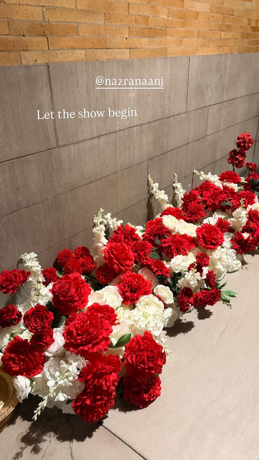 A wall of red and white florals backstage at the Nazranaa NYFW show, captioned let the show begin
