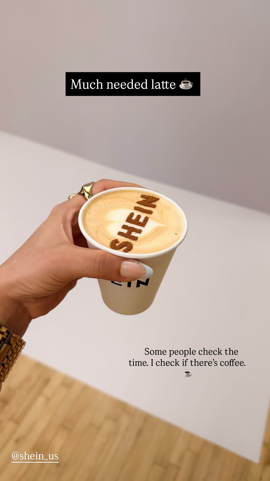 A hand holding a latte with SHEIN written in the foam art, captioned Much needed latte