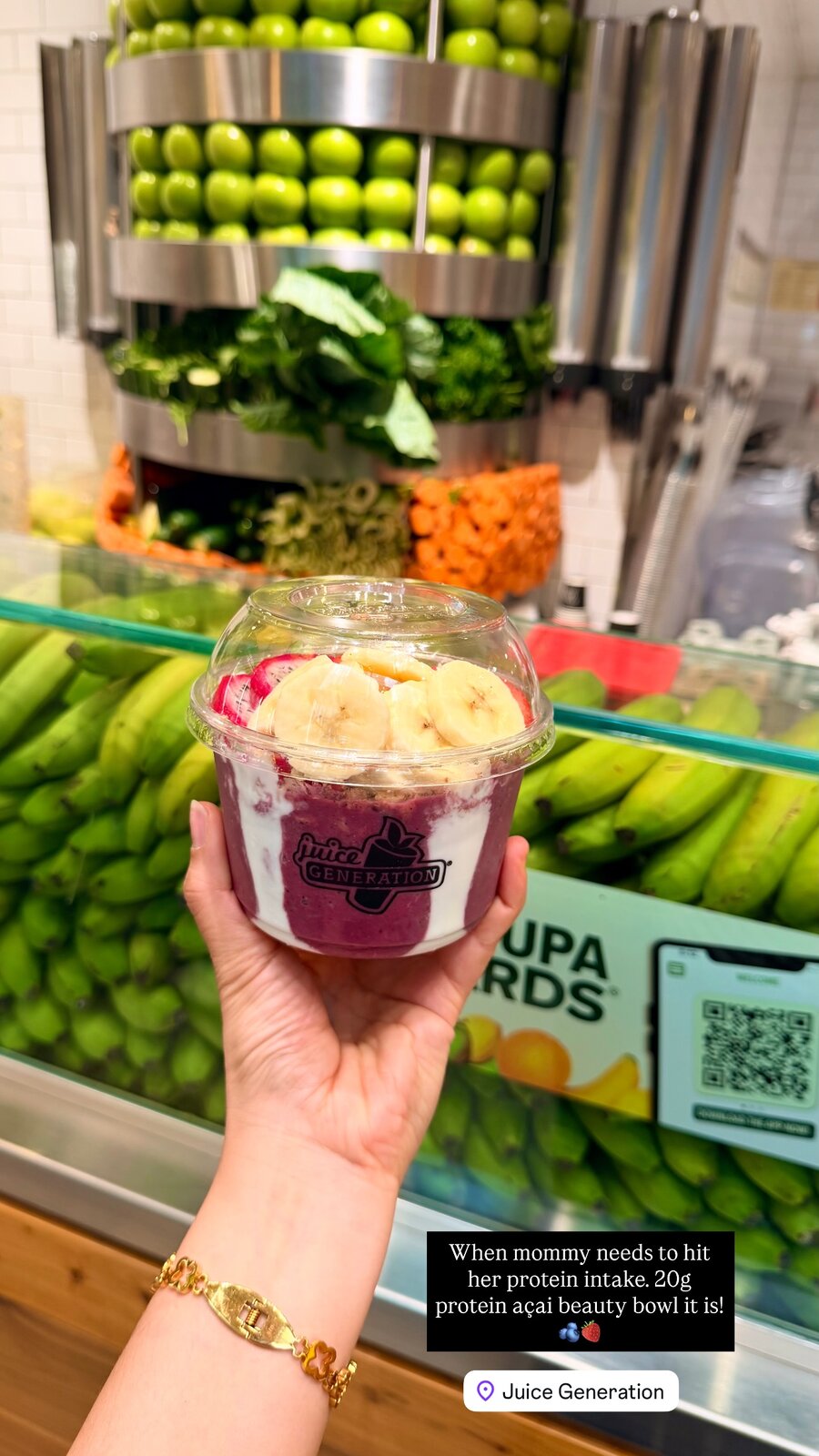 A 20g protein açai beauty bowl topped with banana and strawberry, held up at Juice Generation