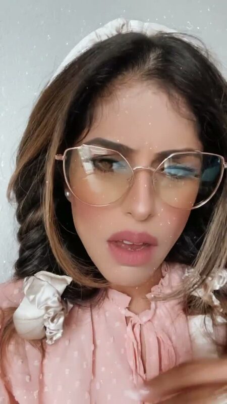 Roopsi Bansal in glasses and a pink ruffle top, showing off soft heatless curls up close