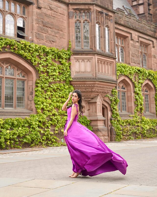 Roopsi Bansal in a magenta silk gown walking in front of an ivy-covered red sandstone building at Princeton, New Jersey