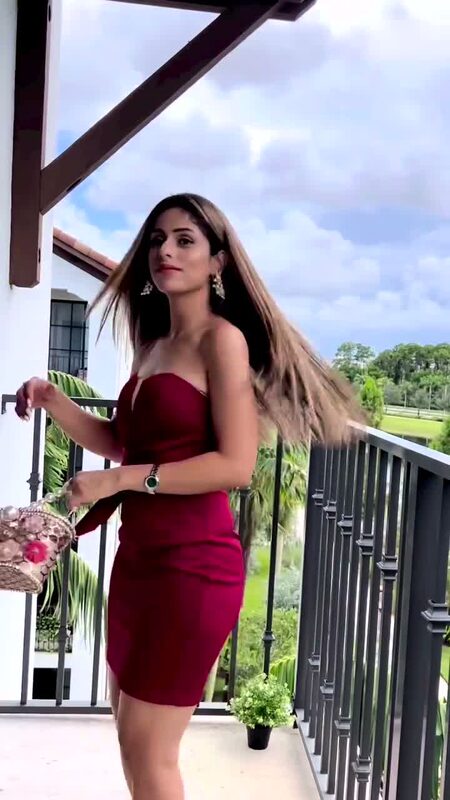 Roopsi Bansal in a burgundy strapless dress on a balcony, hair caught in the wind