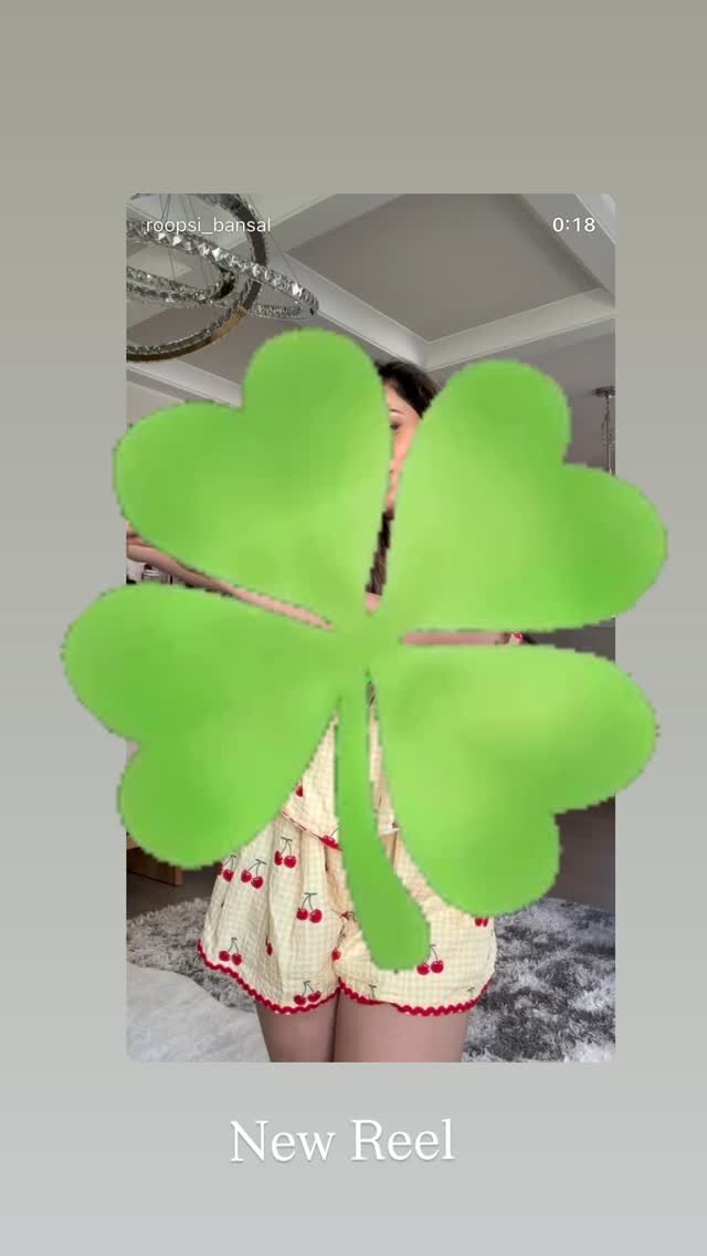 A Story teasing a new reel, with an animated four-leaf-clover sticker and cherry-print pajama shorts visible