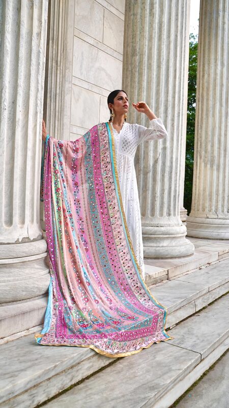 Roopsi Bansal in a white embroidered kurta with a vibrant pink and turquoise mirror-work dupatta draped between marble columns