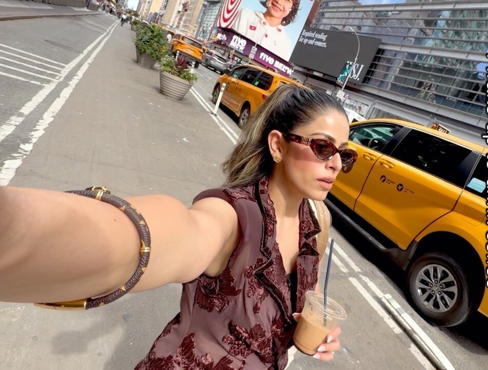 Roopsi Bansal holding an iced coffee on a Midtown street corner next to a yellow cab