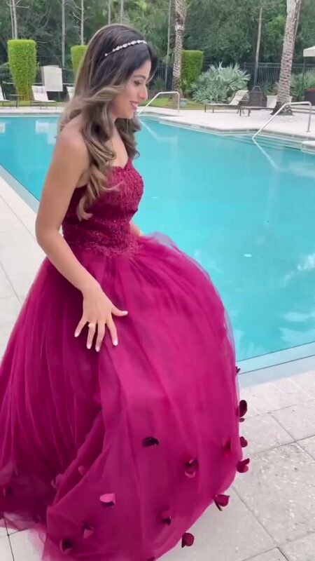 Roopsi Bansal in a magenta petal-covered ball gown from Lunamis, seated poolside mid-transition from a casual pink floral Macy's dress
