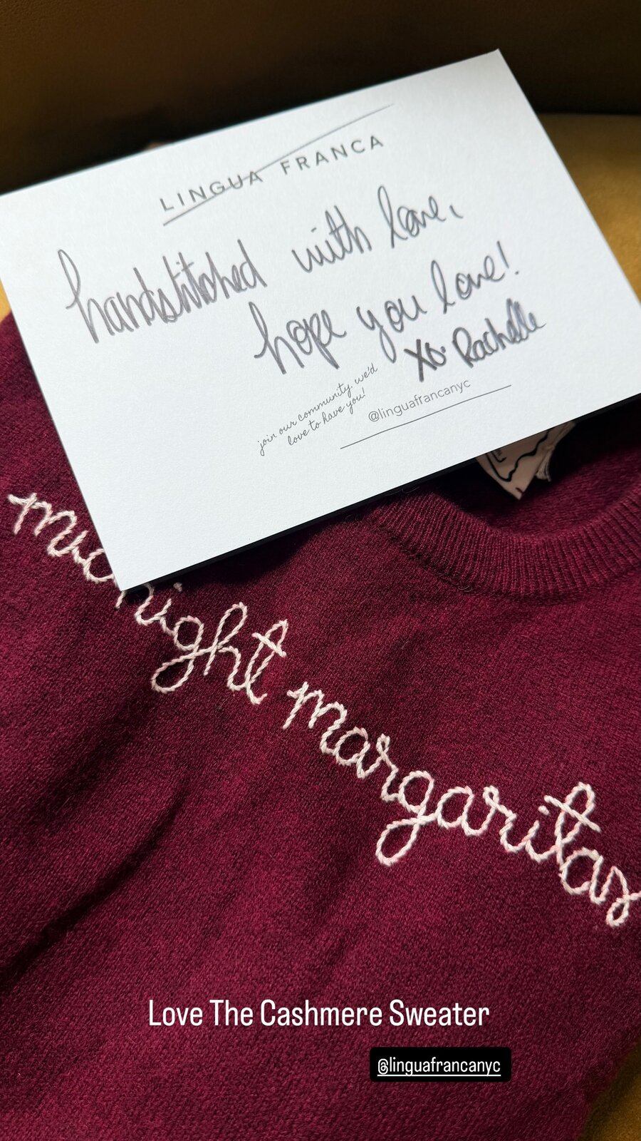 Burgundy cashmere sweater from Lingua Franca hand-embroidered with the words midnight margaritas, with a handwritten thank-you note from the brand resting on top