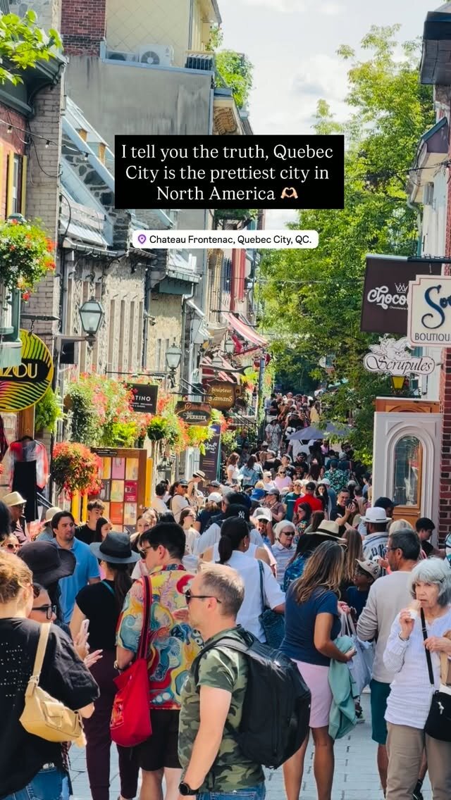 A crowded cobblestone street in Old Quebec lined with flower boxes and shop signs near Chateau Frontenac
