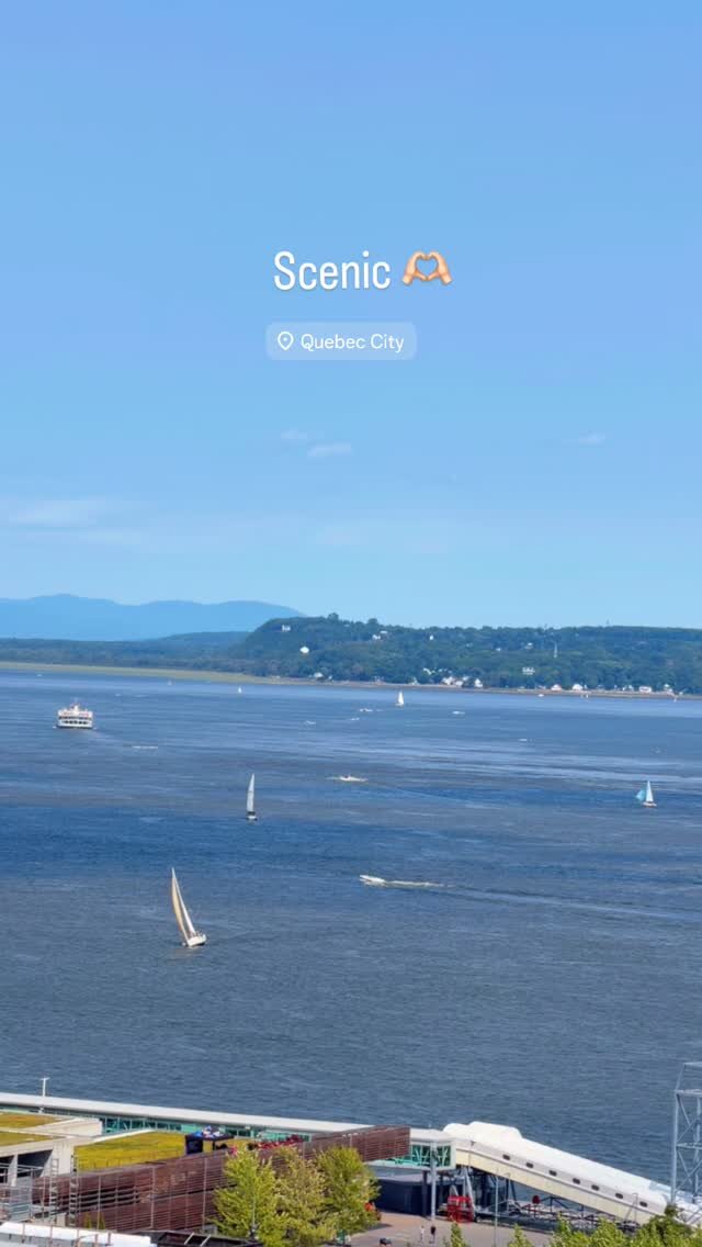 A wide view of the St. Lawrence River with sailboats and a ferry, seen from above in Quebec City