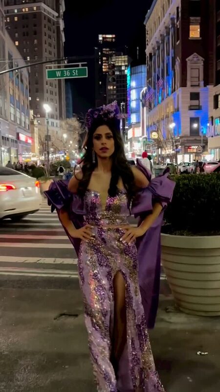 Roopsi Bansal in a purple and gold sequin gown with a floral headpiece standing in a New York City street at night for NYFW