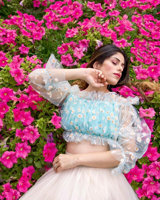 Roopsi Bansal lying back in a bed of magenta petunias at Lodhi Garden, wearing a pale blue daisy-print sheer tulle crop top