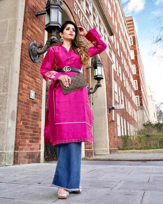 Roopsi Bansal in a hot pink silk kurta with floral embroidery, cinched with a black Gucci logo belt, over flared denim jeans