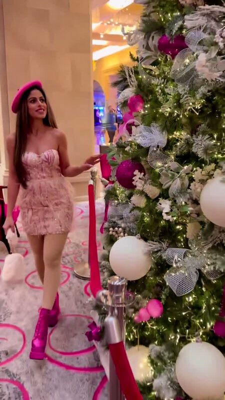 Roopsi Bansal in a pink feather sequin mini dress and pink beret beside a Christmas tree decorated in pink and white at the Borgata Hotel in Atlantic City