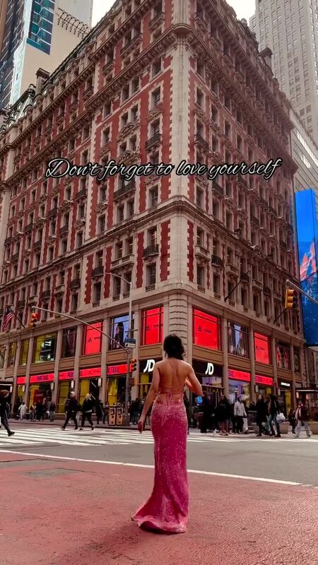 Roopsi Bansal in a backless pink sequin gown with a train, standing in the middle of a Herald Square street intersection in New York